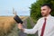 Businessman agronomist farmer in the field holds a wallet with spikelets of wheat