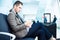 Businessman at airport with smartphone and suitcase