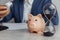 Businessman approves contract in office. Piggy bank with stack of coins and hourglass on desk close-up. Time is money