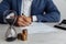 Businessman approves important contract in office. Stack of coins and hourglass on desk close-up. Time is money concept