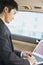 Businessman in Back Seat of Car Typing on Laptop