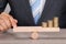 Businessman balancing coins on wooden seesaw