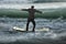 Businessman balancing on money boat floating in ocean with waves