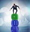 Businessman balancing on top of dice stack in uncertainty concep