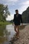 businessman with beard in suit, without pants, walks along river near mountain landscape to relieve stress after hard working