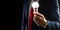 A businessman in a black suit is holding a light bulb in his hand illuminated on a black background with copy space