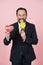 Businessman in black suit licking lollipop. Manager face emotion with red box in studio. Man makes present and loves candy