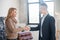 Businessman in a black suit welcoming a female customer