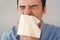 Businessman blows his nose in a rag. Young man sneezes into tissue. guy is sick, has a cold or allergic reaction. Coronavirus,