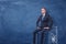 Businessman on blue chalkboard background sitting on a strongbox drawn in white.