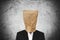Businessman with brown paper bag on head, on dark concrete texture background