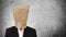 Businessman with brown paper bag on head, on dark concrete texture background, with copy space
