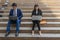 Businessman and business women sit on the staircase and typing word into laptop, concept of work hard