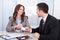 Businessman and businesswoman exchanging visiting card at office desk