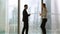 Businessman and businesswoman meeting in office standing by full-length window