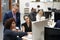 Businessman And Businesswomen Working At Computer On Desk In Open Plan Office