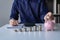 Businessman calculating savings with pile of coins on table, importance of bank