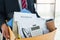 Businessman carrying packing up all his personal belongings and files into a brown cardboard box to resignation in modern office,