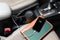 A businessman cell phone on the passenger seat and plugged into the cars charging port with coffee cup, and notebook