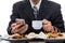 Businessman checking the news from mobile phone and taking coffee cup