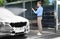 Businessman cleaning auto with high pressure water jet at car wash