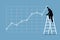 Businessman climbing up on a ladder to adjust an uptrend graph chart on a wall.