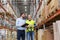 Businessman with clipboard and loader at warehouse