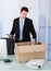 Businessman collecting office supply in cardboard box at desk