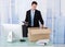 Businessman collecting office supply in cardboard box at desk