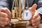 Businessman Covering Stopwatch And Coins On Weighing Scale