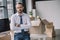 businessman with crossed arms looking at camera while sitting on table with boxes