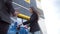 Businessman in a dealership shows a girl how to charge an electric car at a charging station