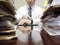 Businessman at Desk with Files Pointing at Watch