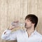 Businessman With Drinking Water From Bottle Against Wooden Wall