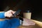 Businessman drinks coffee in a cafe, close-up holds a disposable paper glass, using smartphone while having rest, break or lunch.