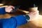 Businessman drinks coffee in a cafe, close-up holds a disposable paper glass, using smartphone while having rest, break or lunch.