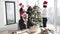 Businessman employee in santa hat sitting at desk using laptop in christmas decorated office.