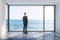 Businessman in empty loft room with big window in floor and ocean view