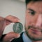 Businessman examines a Swiss coin with five francs.