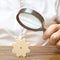 Businessman examines a wooden gear through a magnifying glass. A cog from a big business machine. Every little thing is important