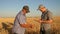 Businessman and farmer with tablet working as a team in the field. agronomist and farmer are holding a grain of wheat in