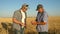 Businessman and farmer with tablet working as a team in field. agronomist and farmer are holding grain of wheat in their