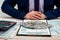 A businessman fills out an individual 1040 tax form and counts dollars. Male hands writing on paper with calculator in office