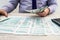 A businessman fills out an individual 1040 tax form and counts dollars. Male hands writing on paper with calculator in office