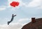 Businessman floating with balloons by Roof with chimney and blue sky