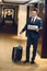 businessman in formal suit standing in hotel corridor with a suitcase