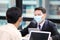 Businessman in formal wear with protective facial mask discussing with colleague in business office following new normal