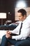 Businessman in formal wear sitting on bed in hotel room, writing notes