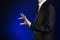 Businessman and gesture topic: a man in a black suit and white shirt shows a hand pinch on a dark blue background in studio