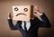 Businessman gesturing with cardboard box on his head with sad fa